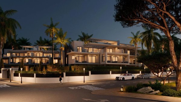 Modern appartementencomplex 's nachts met palmbomen, gelegen in Estepona, Costa del Sol.