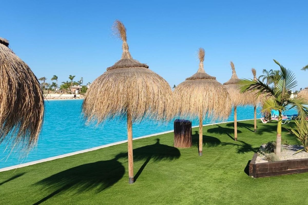 Tijken parasols langs het zwembad met weelderig groen in Torre Pacheco, Costa Calida.