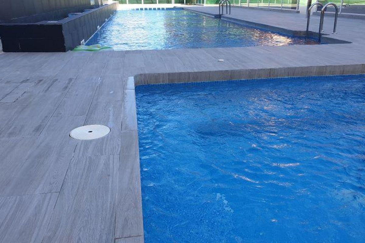 Heldere en uitnodigende zwembadruimte met blauw water, perfect om te ontspannen bij het gelijkvloerse appartement.