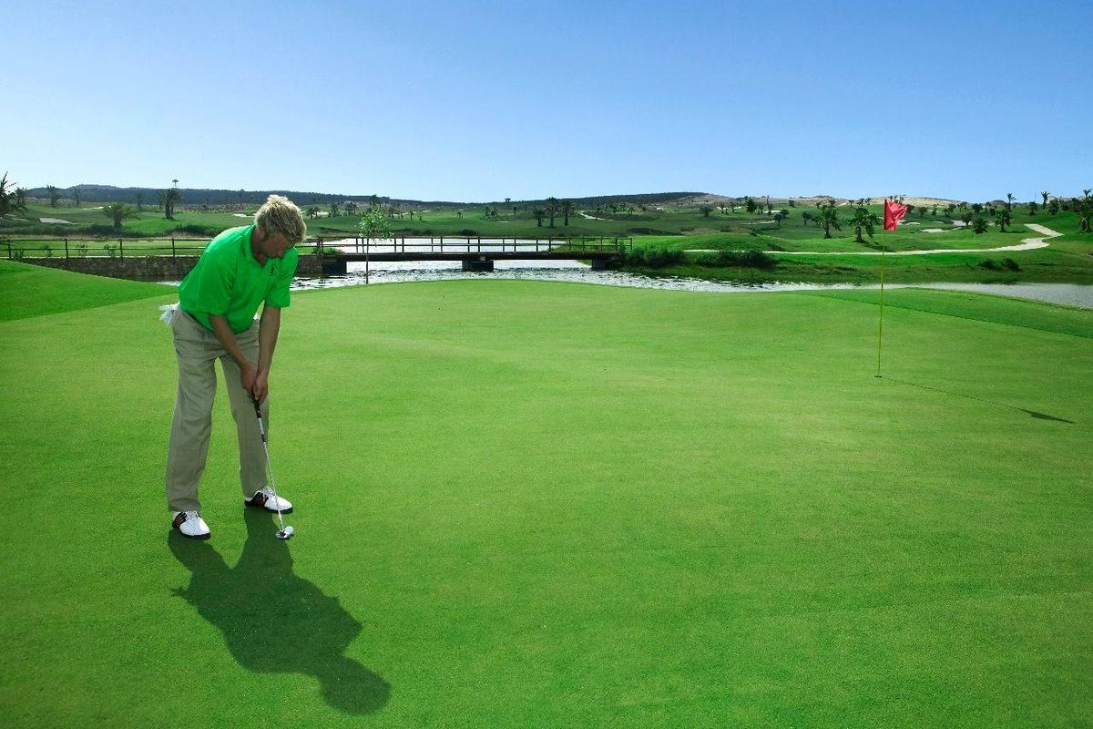 Golfer putt op een goed onderhouden green op een schilderachtige golfbaan in de Costa Blanca.