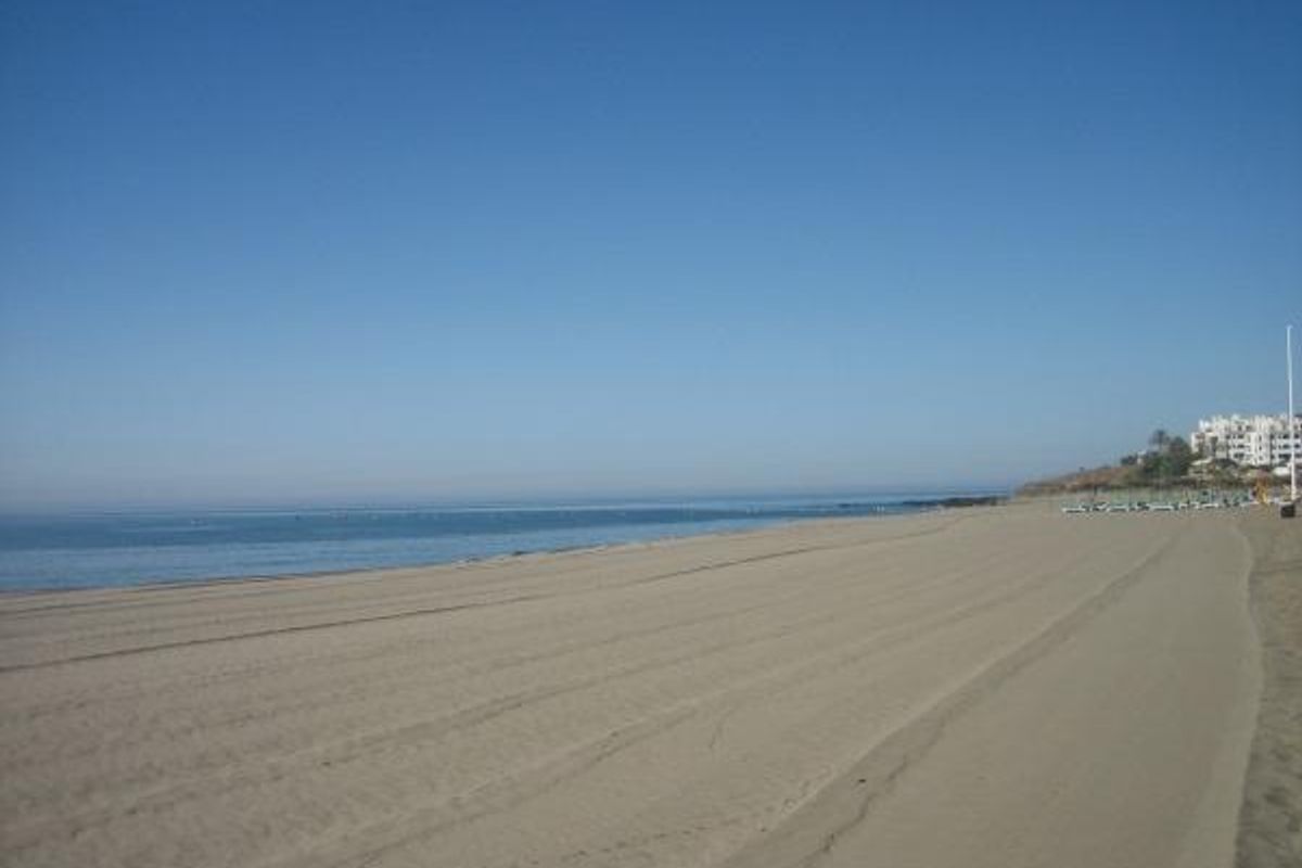 Een serene strandview met kalme wateren en een zandstrand nabij Mijas, Costa del Sol.