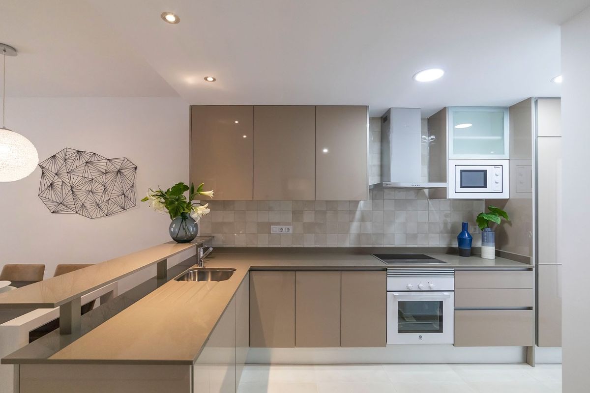 Moderne open keuken met neutrale tinten, houten aanrecht en geometrische wandkunst in appartement in Mar de Pulpi