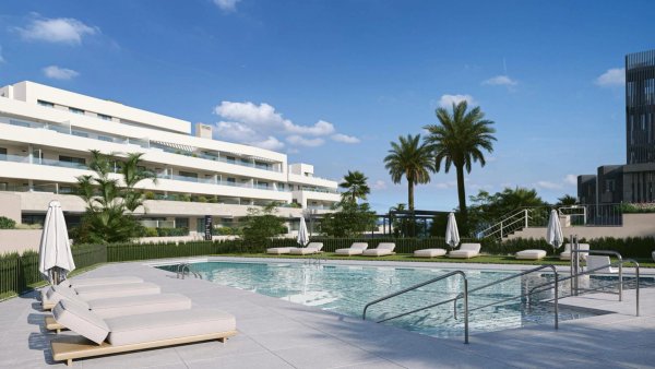 Buitenpool met ligstoelen en palmbomen bij een modern appartementengebouw in Estepona, Costa del Sol.