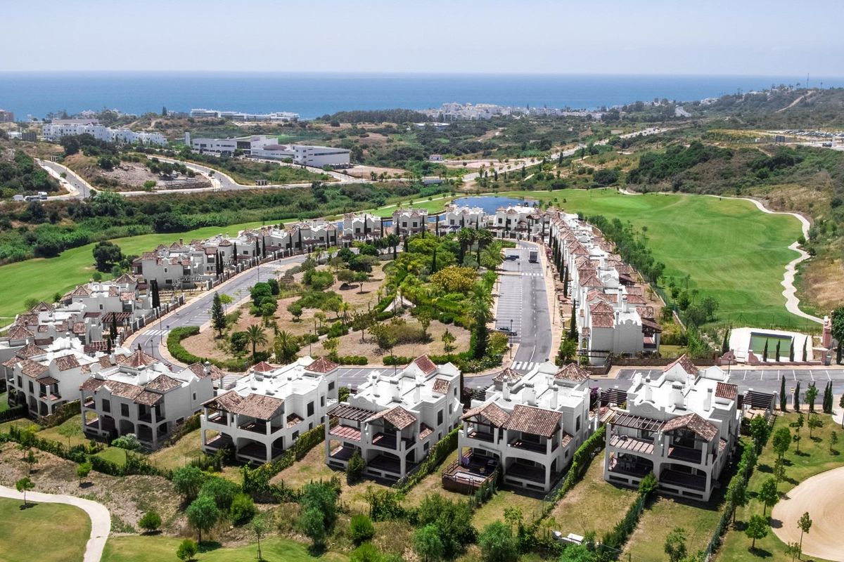 Luchtfoto van een pittoreske gemeenschap met villa's in Estepona, Costa del Sol, nabij weelderige landschappen en oceaan.