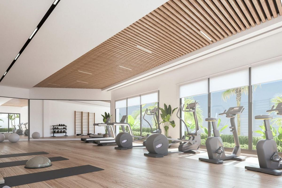 Ruime gym met cardioapparatuur en natuurlijk licht in een luxe gebouw in Marbella, Costa del Sol.