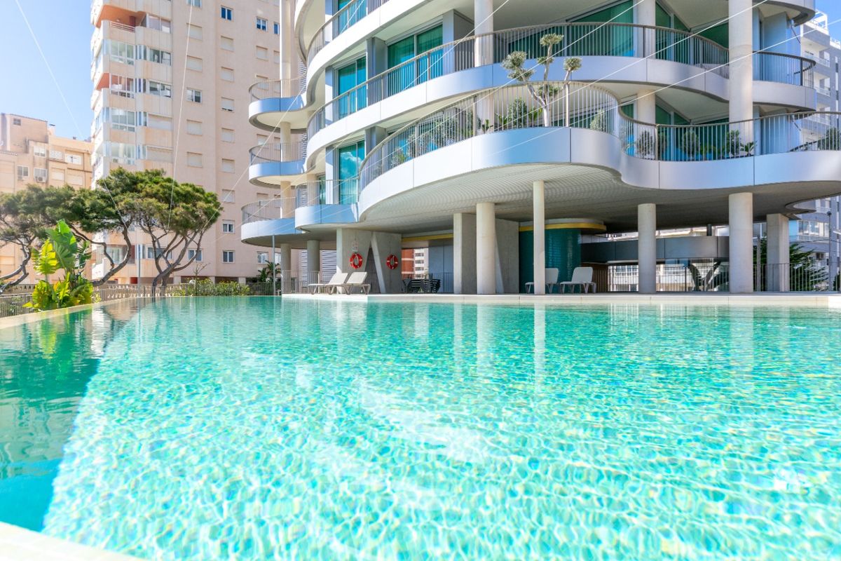 Mooi aangelegd groen gebied met uitzicht op het zwembad, dat de moderne architectuur van de appartementen in Calpe toont.