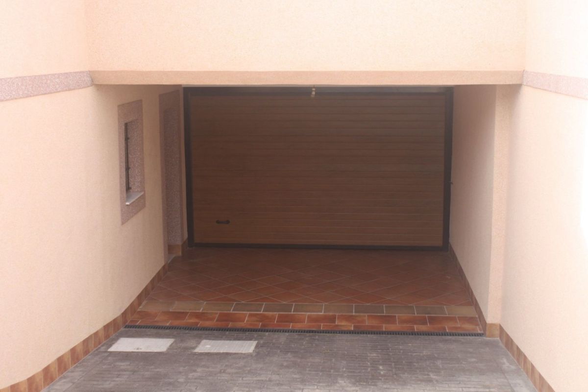 Een afgesloten garage in de townhouse, met betegelde vloer en een grote deur in Torrevieja.