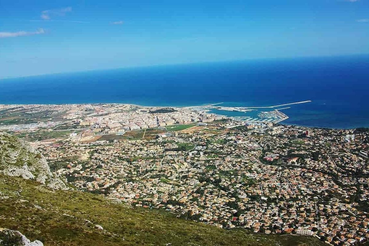 Panoramic shot of Denia's coastline showcasing buildings, beaches, and the sea.