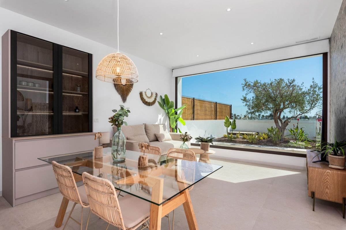 Ruime woonkamer en eetruimte met grote ramen die uitzicht op de tuin bieden in deze villa in Los Alcazares.