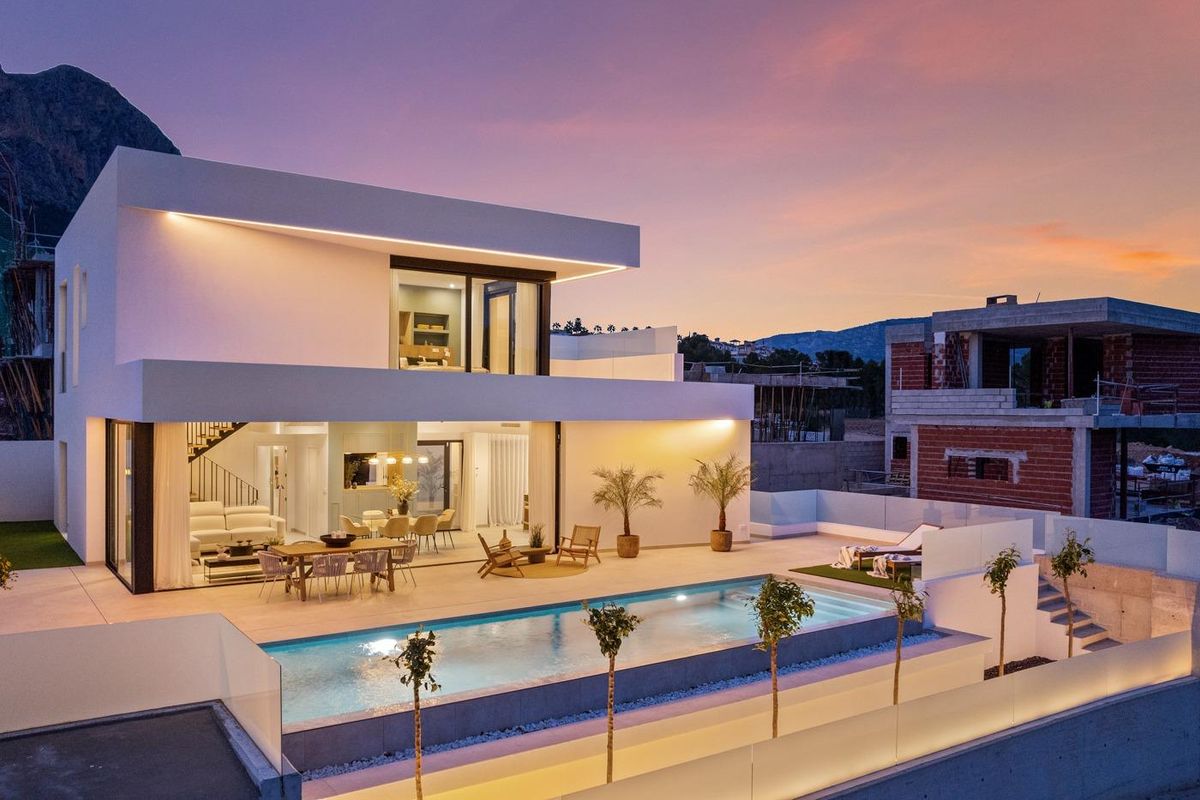 Stijlvolle villa in Polop die haar zwembad en buitenlounge laat zien bij schemering.