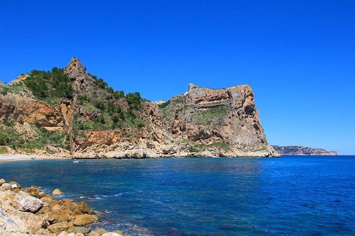 Kalm turquoise water en rotsachtige kliffen nabij Benitachell, met prachtige natuur van Costa Blanca.
