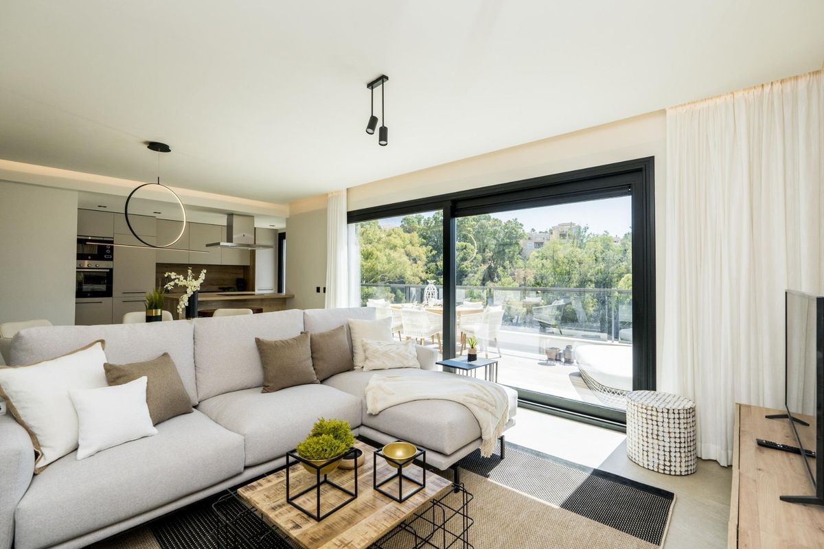 Lichte woonkamer van een penthouse in Marbella, met een ruime indeling en grote ramen die het groen tonen.