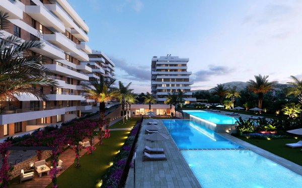 Buitenzicht op een modern appartementencomplex met twee zwembaden en tropische tuin in Villajoyosa, Costa Blanca.