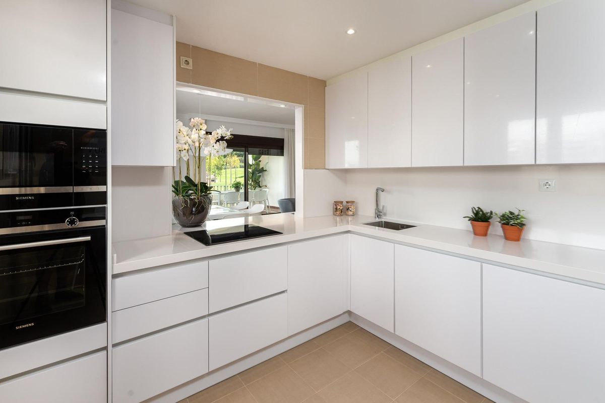 Strakke moderne keuken met witte kasten en planten, gelegen in een drie-slaapkamer villa in Estepona.
