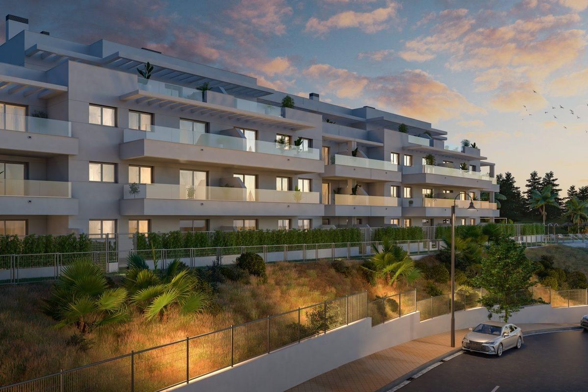 Modern appartementen façade bij schemering, met zachte verlichting en weelderige beplanting in Mijas, Costa del Sol.