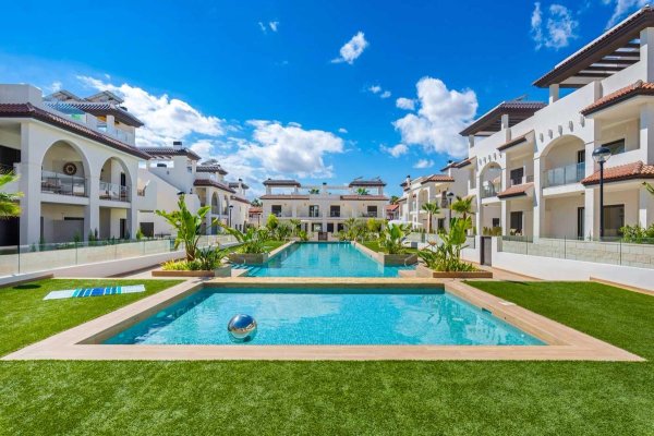 View of the communal pool surrounded by lush gardens in Rojales, Costa Blanca South, Spain.