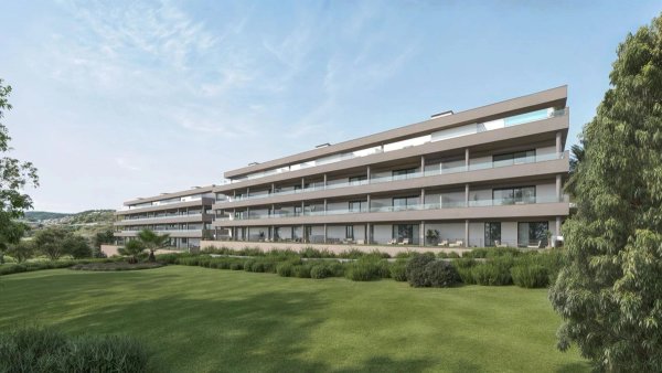 Buitenkant van een modern 1-slaapkamerappartement in Estepona, omringd door groene tuinen.