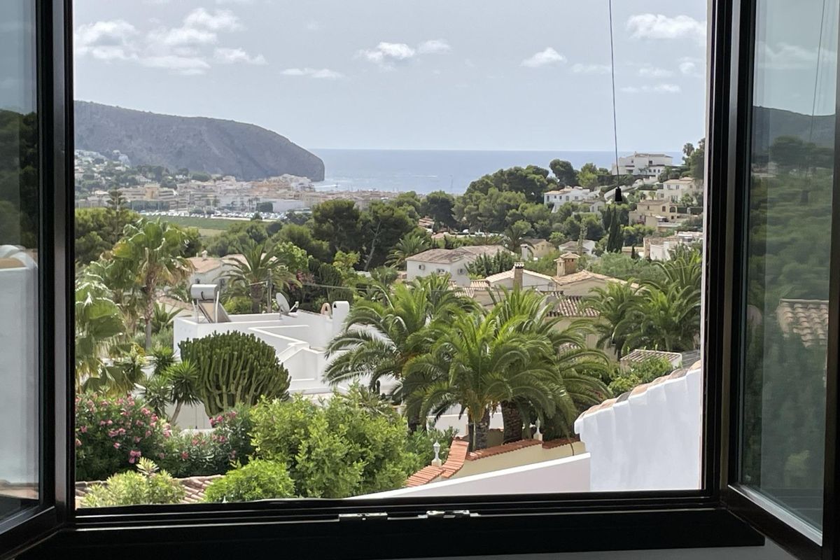 Schilderachtig uitzicht vanuit een raam met palmbomen en heuvels in het mooie Moraira Teulada.