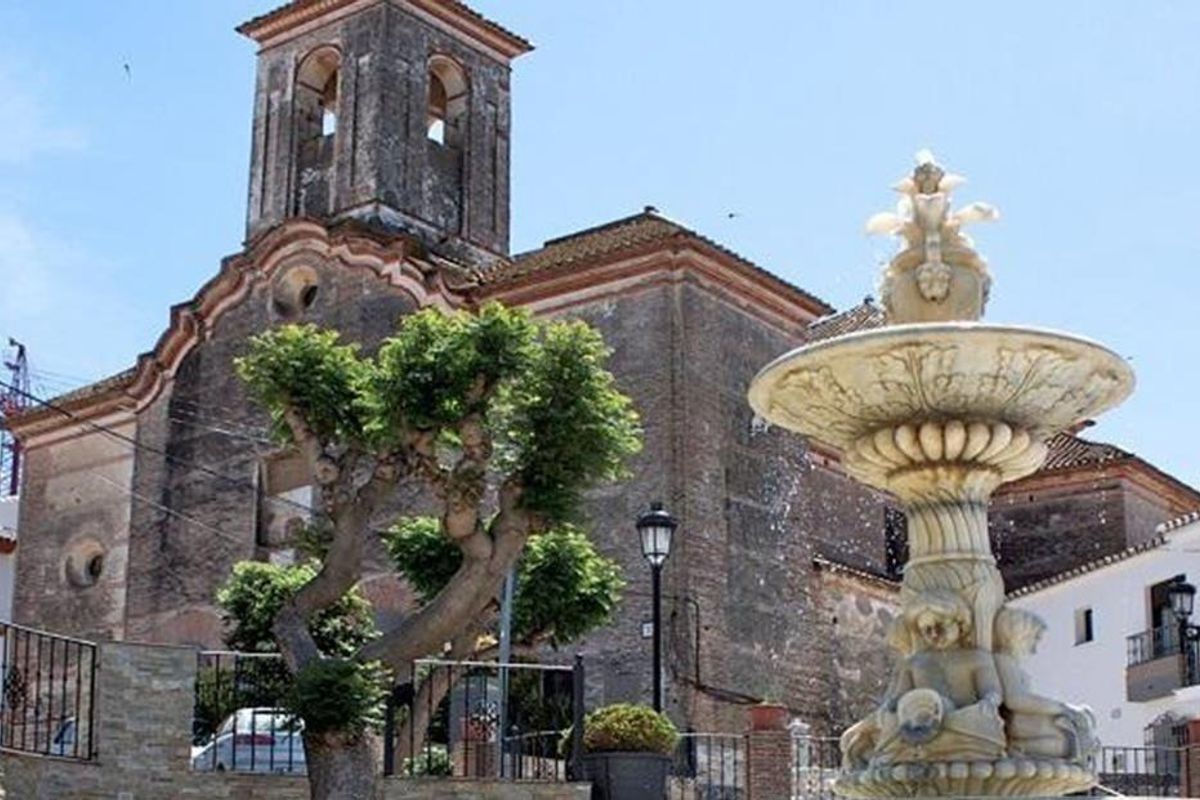 Charmant plein in Manilva, met een historische kerk en een decoratieve fontein.