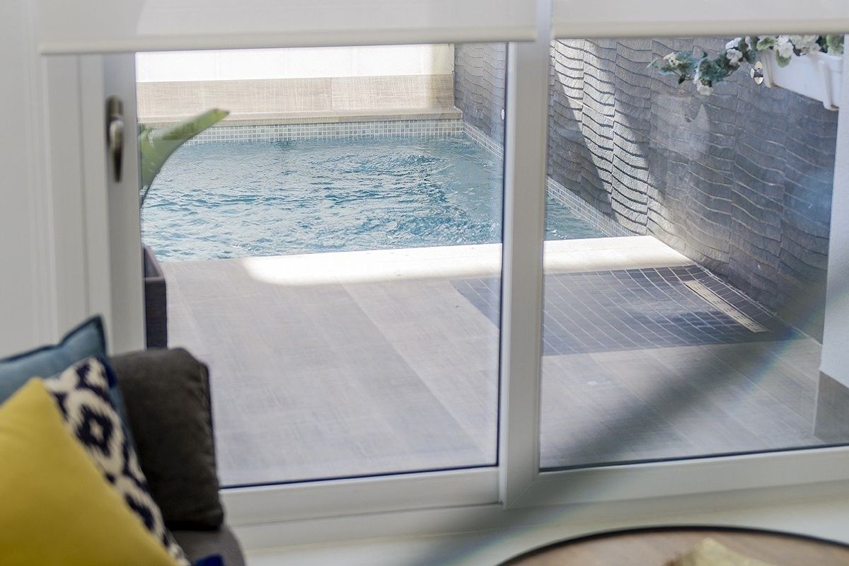 Uitzicht op het privézwembad vanuit de gezellige woonkamer in een moderne villa in Cartagena, Costa Calida.