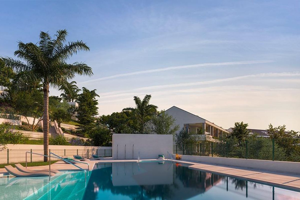 Zwembad omgeven door weelderige tuinen bij een penthouse in Benalmádena, Costa del Sol, met palmbomen.