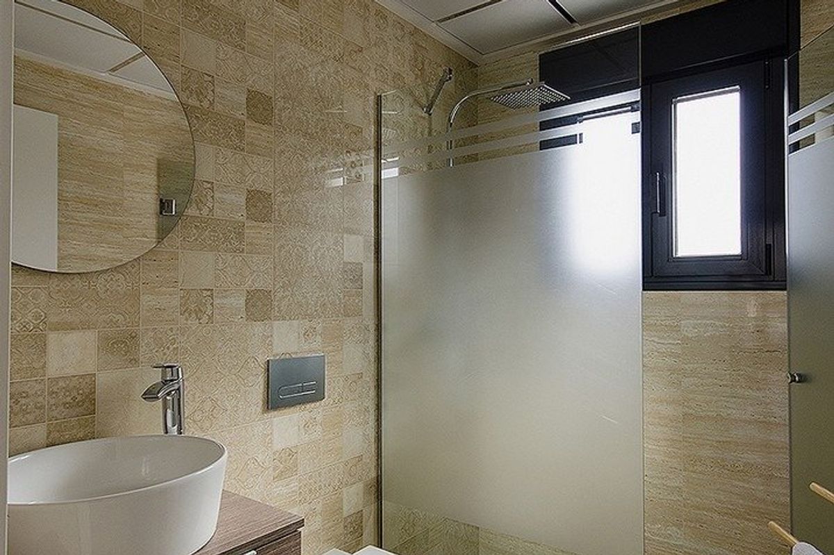 Chique badkamer in een 4-slaapkamer villa in Cartagena, met elegante tegels en een eigentijdse glazen douche.