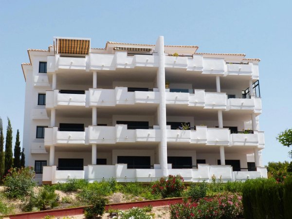 Buitenzicht op een modern appartementencomplex in Orihuela Costa met meerdere balkons en groen.