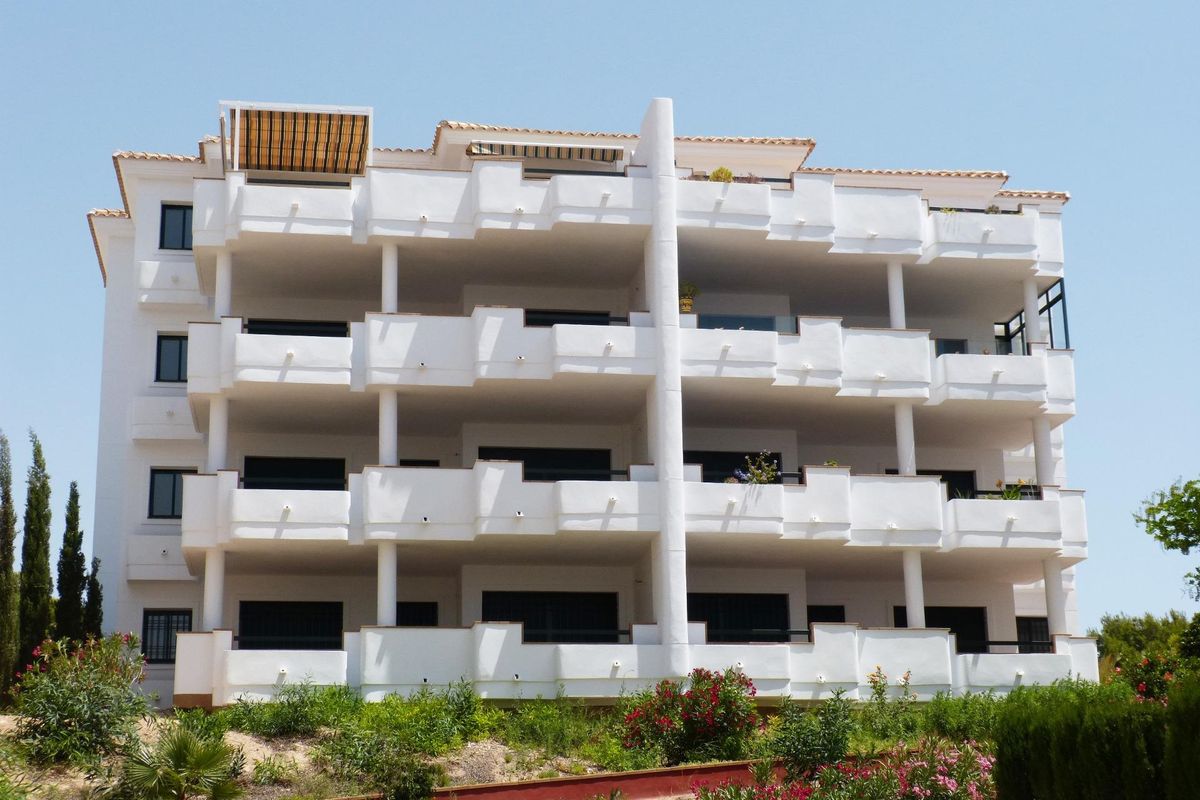 Buitenzicht op een modern appartementencomplex in Orihuela Costa met meerdere balkons en groen.