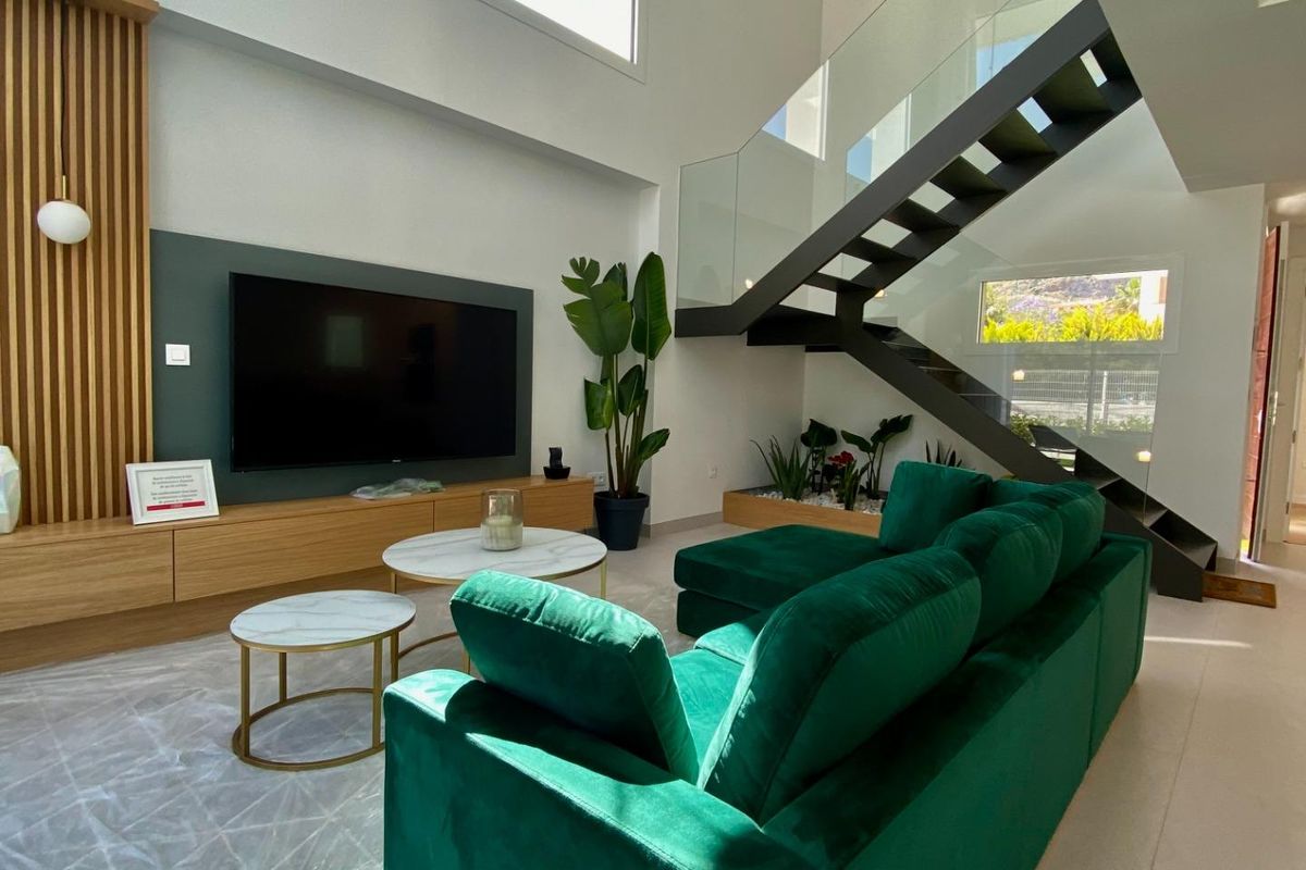 Elegante woonkamer met een groene bank en trappen, die licht en modern design in Finestrat toont.