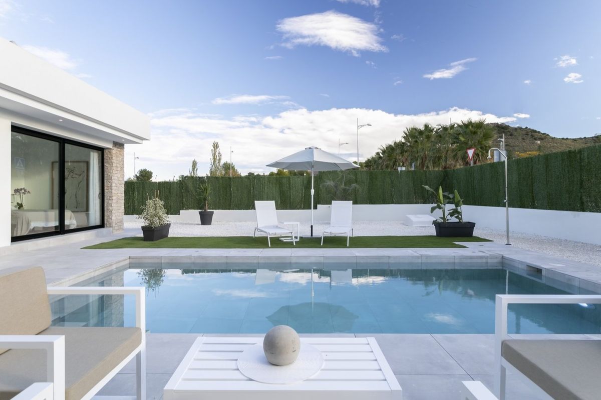Uitnodigende poolside view van een moderne villa in Calasparra, met ontspannende ligstoelen.