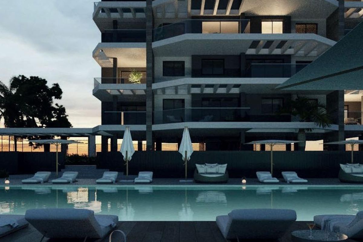 Avondzicht op het verlichte zwembad en appartementgebouw, dat luxe wonen in Calpe, Spanje toont.