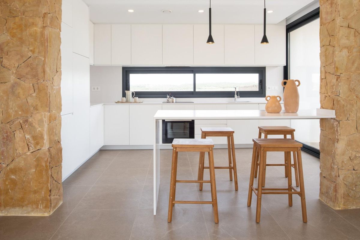 Heldere keuken met witte kasten en een moderne bar met stoelen in een villa in Orihuela Costa.