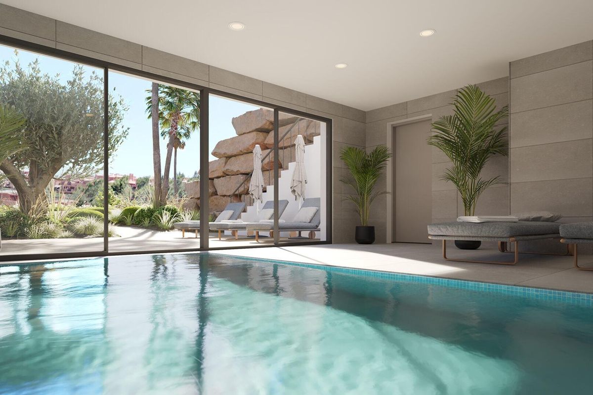 Zwemzaal binnen met grote ramen en zonnig uitzicht in een wooncomplex in Estepona, Costa del Sol.