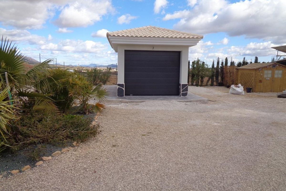 Garage met een donkere deur en groen in Pinoso, Costa Blanca Zuid, Spanje.