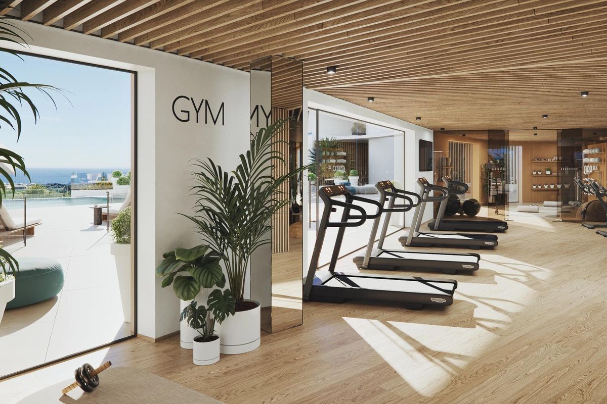 Heldere gymruimte met moderne apparatuur en uitzicht op de oceaan in een 3-slaapkamer complex in Mijas.