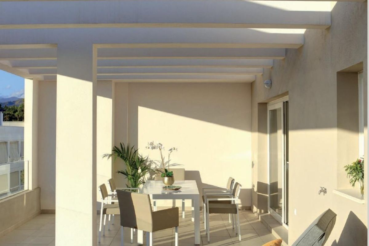 Ruim terras van een modern appartement in Marbella, met comfortabele ligbedden en eetset.
