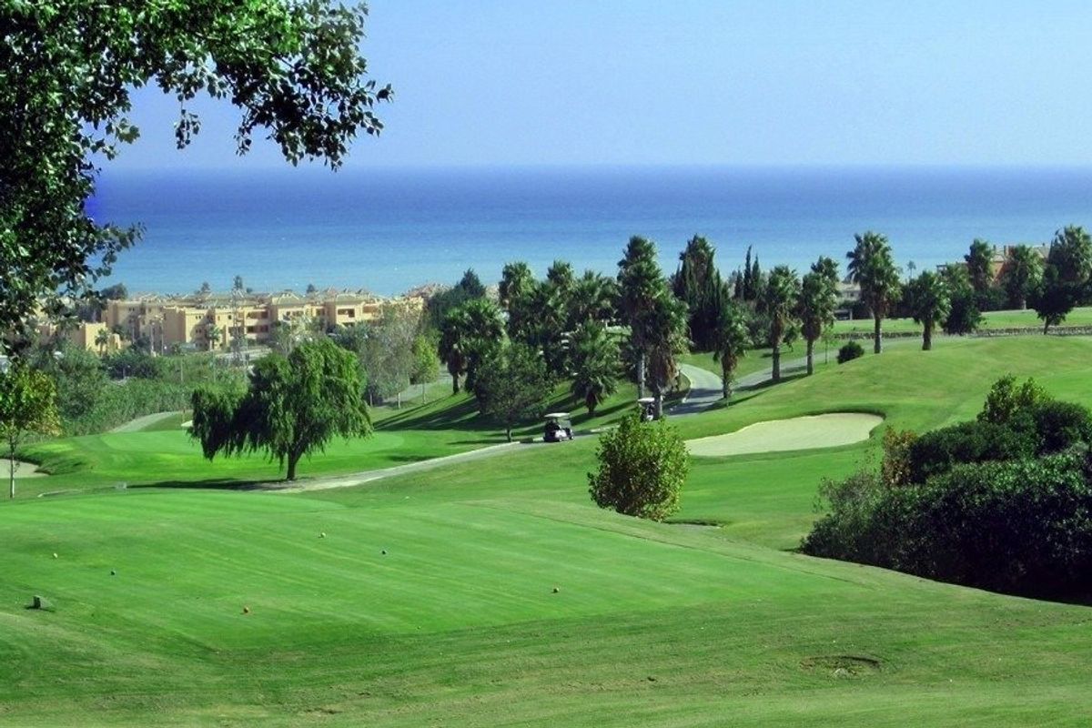 Schilderachtig golfbaanlandschap met berkenbomen, groene fairways, zeezicht en woongebouwen in Manilva