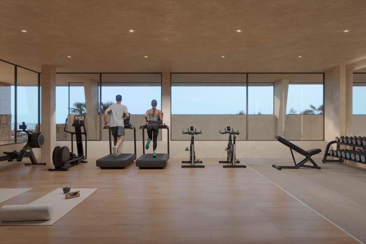 Moderne gym met fitnessapparatuur en grote ramen, gelegen in een appartementencomplex in Torremolinos.