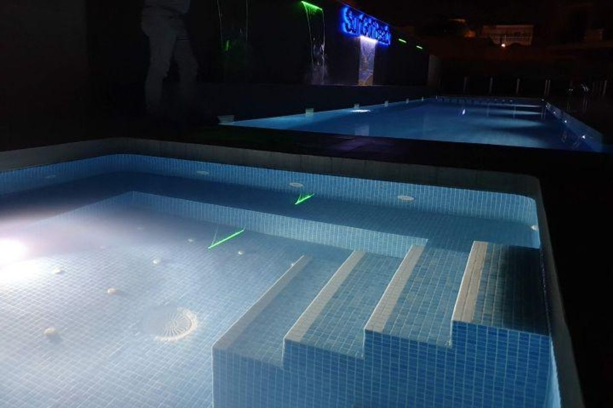 Verlichte zwembadruimte van de woning, met modern ontwerp en een rustige sfeer 's nachts.