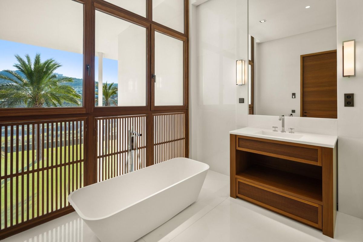 Stijlvolle badkamer met een vrijstaand bad en brede ramen met uitzicht op de tuin in de villa in Casares.