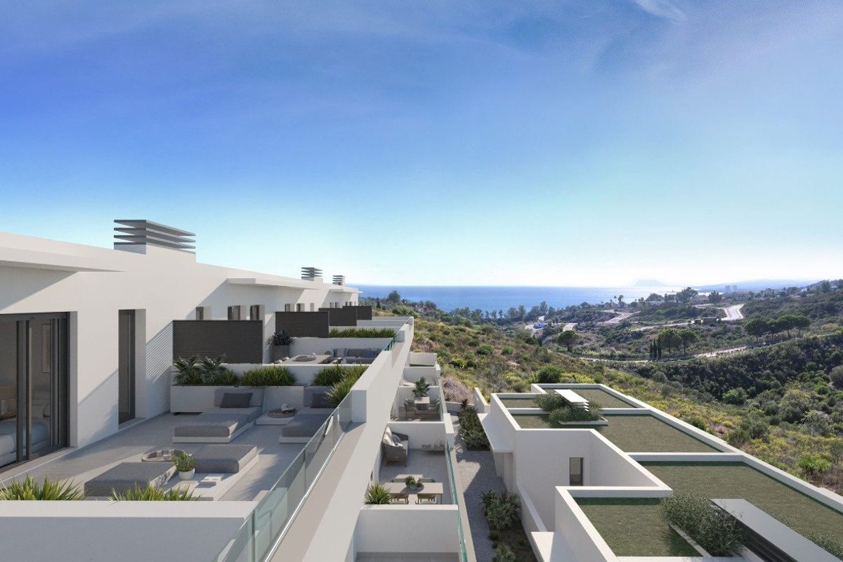 Terraced balconies on modern white townhouses, offering outdoor living and partial sea views in Manilva, Costa del Sol.