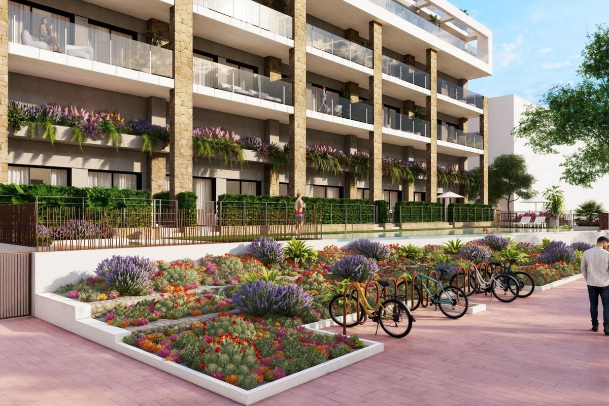 Kleurrijke tuin met bloemen en fietsen voor het appartementencomplex in Villajoyosa.