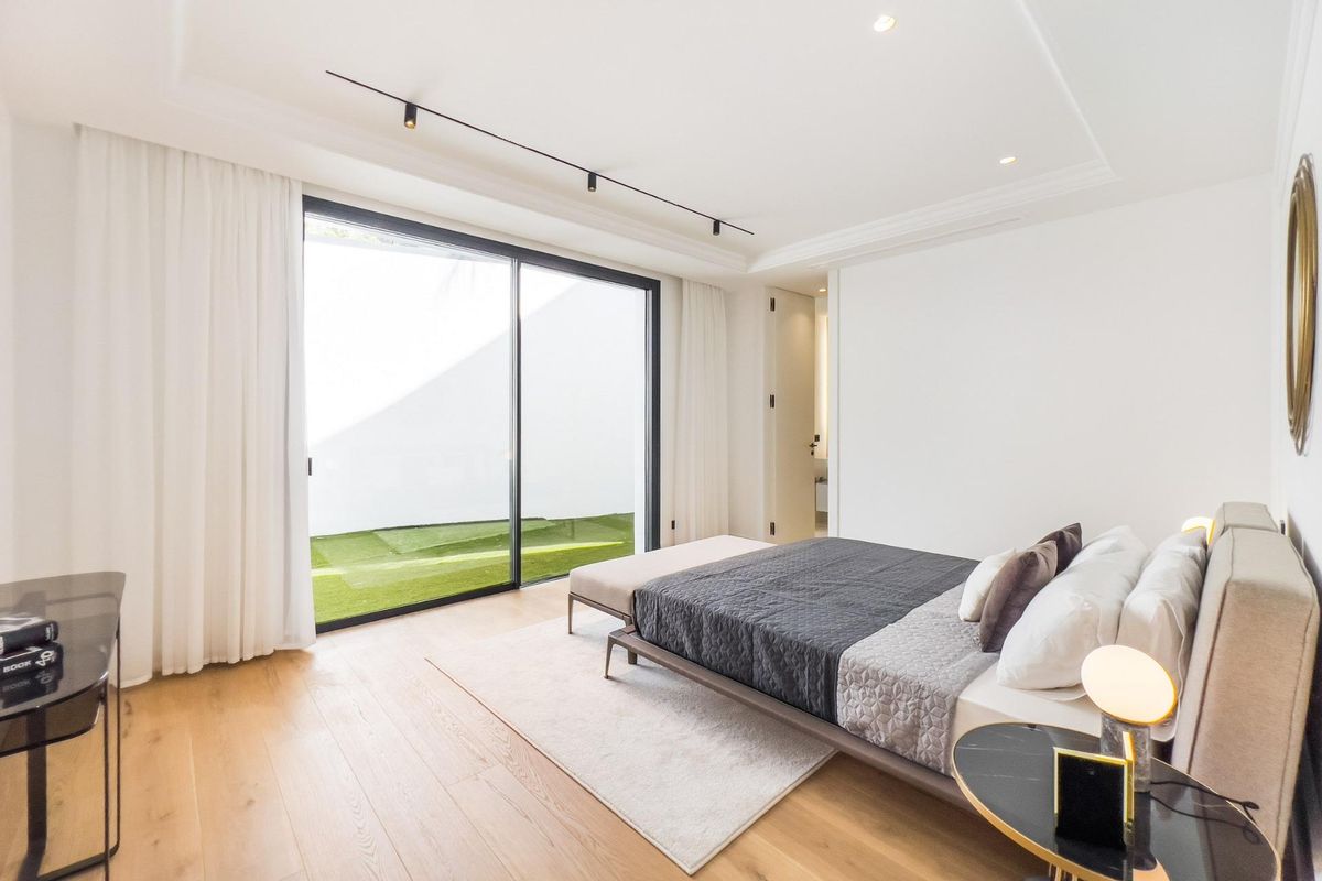 Stijlvolle slaapkamer in een villa in Marbella met een groot raam naar een privétuin.