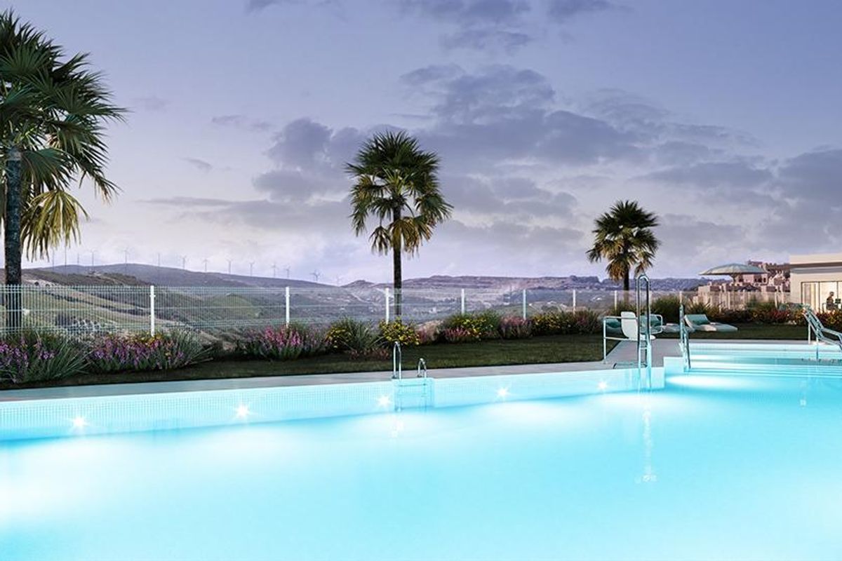 Verlichte zwembad bij schemering omringd door weelderig groen in Manilva, Costa del Sol, Spanje.