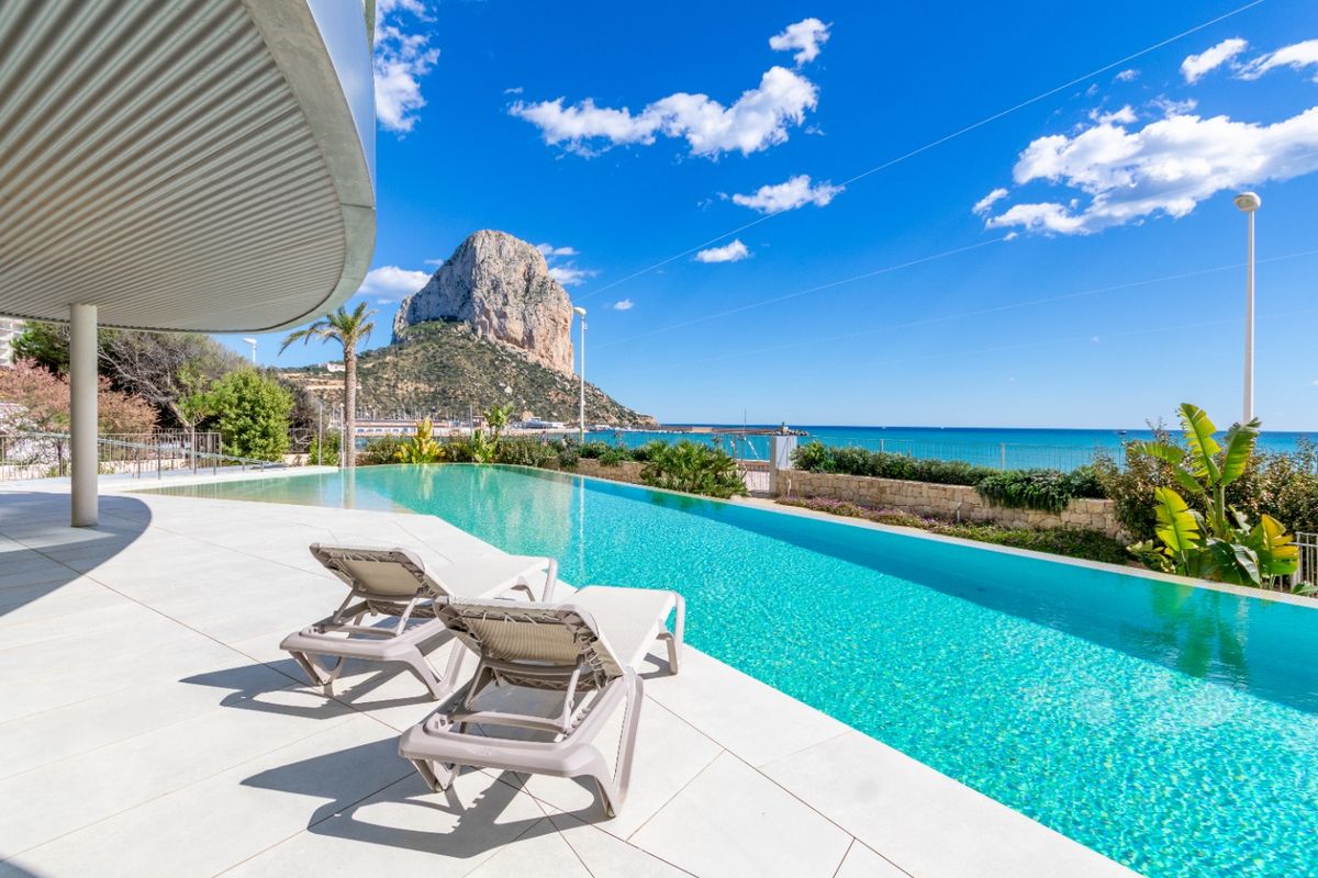 Adembenemend uitzicht op het infinity pool met ligbedden in Calpe, Costa Blanca, met de Peñon de Ifach.