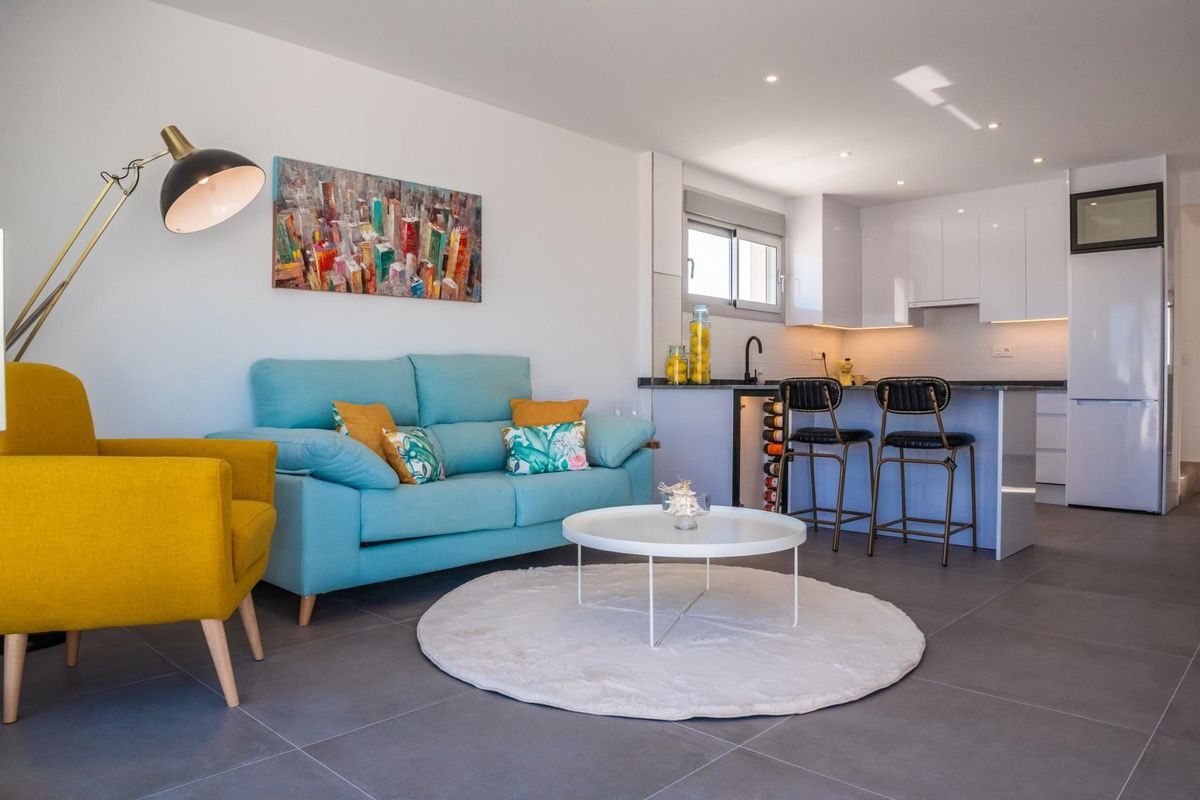 Heldere woonkamer met een blauwe bank en moderne keuken in de 3-slaapkamer villa, Los Alcazares, Spanje.