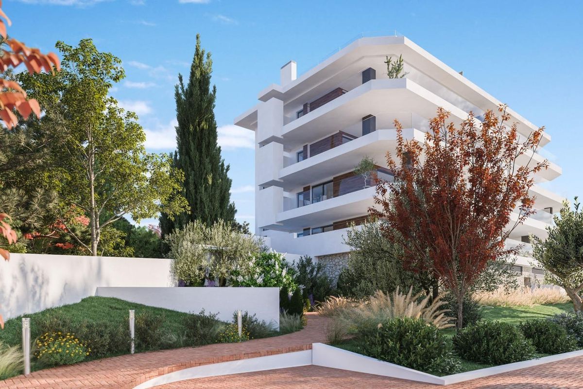 Buitenaanzicht van een modern 3-slaapkamer appartementgebouw in Fuengirola, met aangelegde tuinen en een heldere lucht.