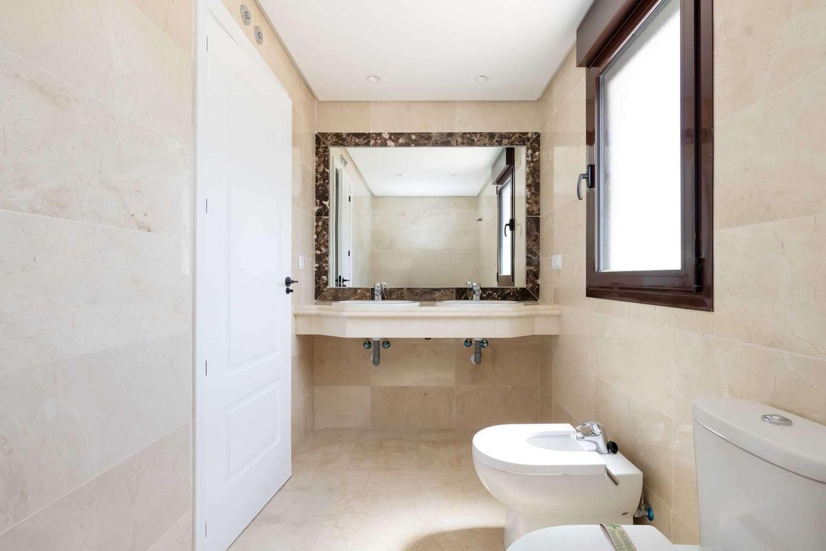 Elegant badkamer in een townhouse in Estepona met moderne armaturen, natuurstenen afwerking en grote spiegel.