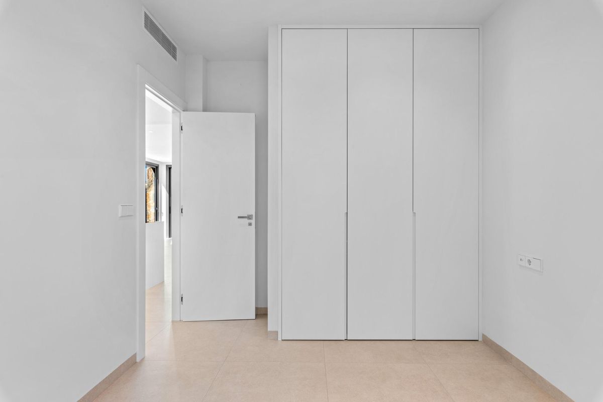 Eenvoudige en heldere slaapkamer in een bungalow in Pilar de La Horadada, ontworpen met voldoende kastruimte.