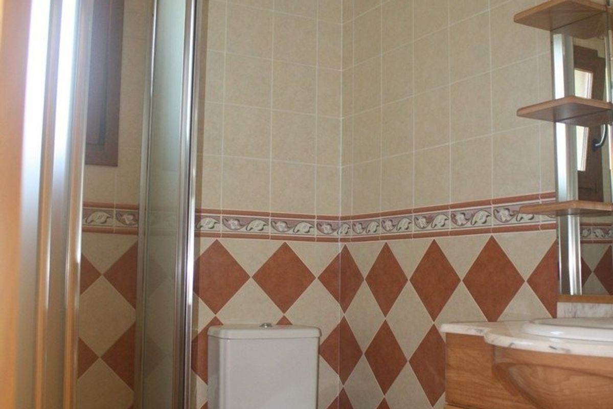 Goed uitgeruste badkamer in de villa, met betegelde wanden en voldoende verlichting voor comfort.